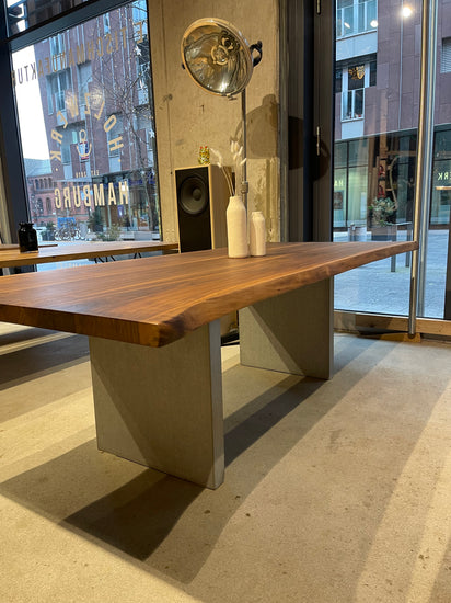 Stylischer Esstisch aus Nussbaum mit Tischgestell aus Beton in Wangenform